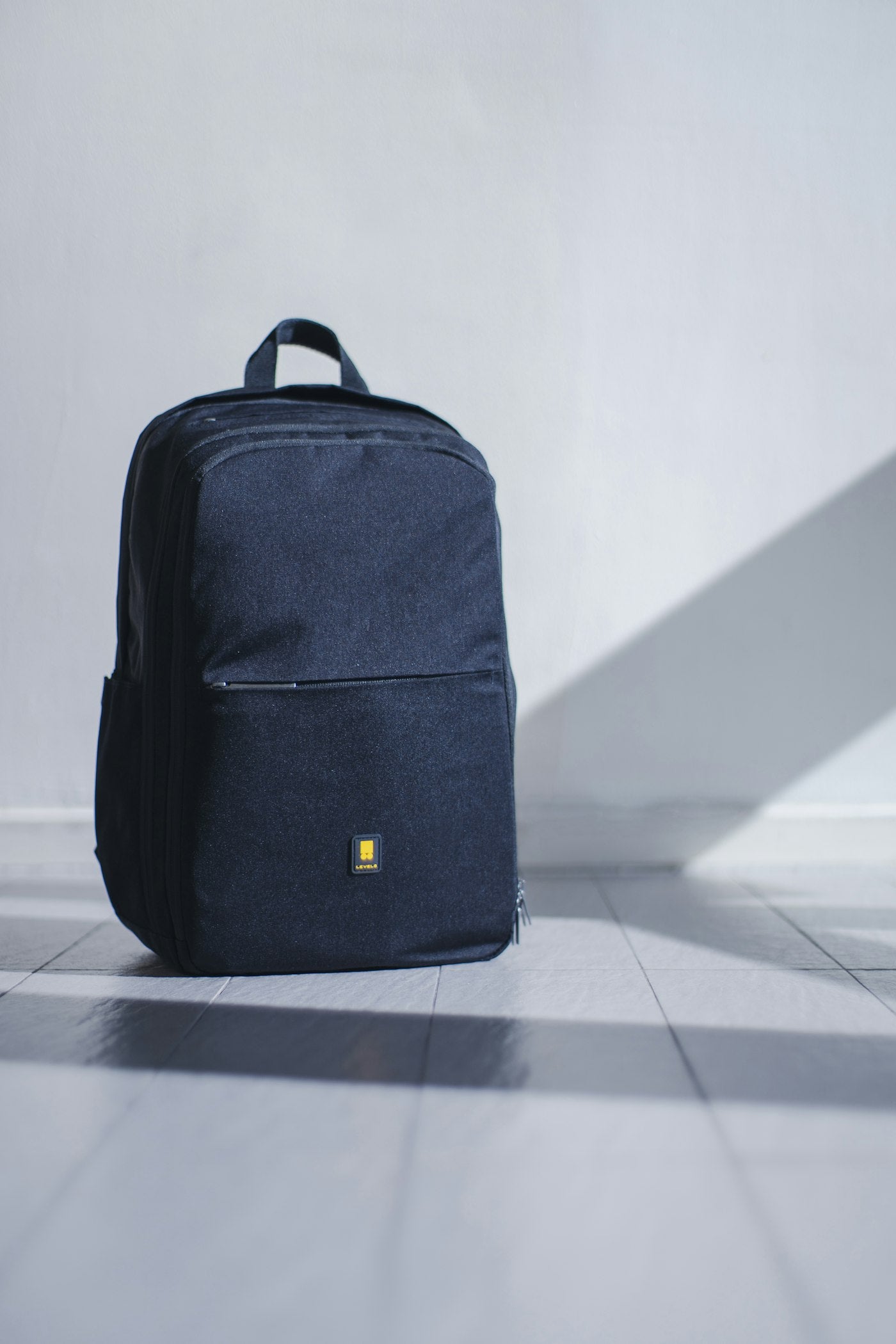 A navy backpack against a plain wall