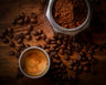 Espresso, scattered beans and a jar of ground coffee on a wooden table