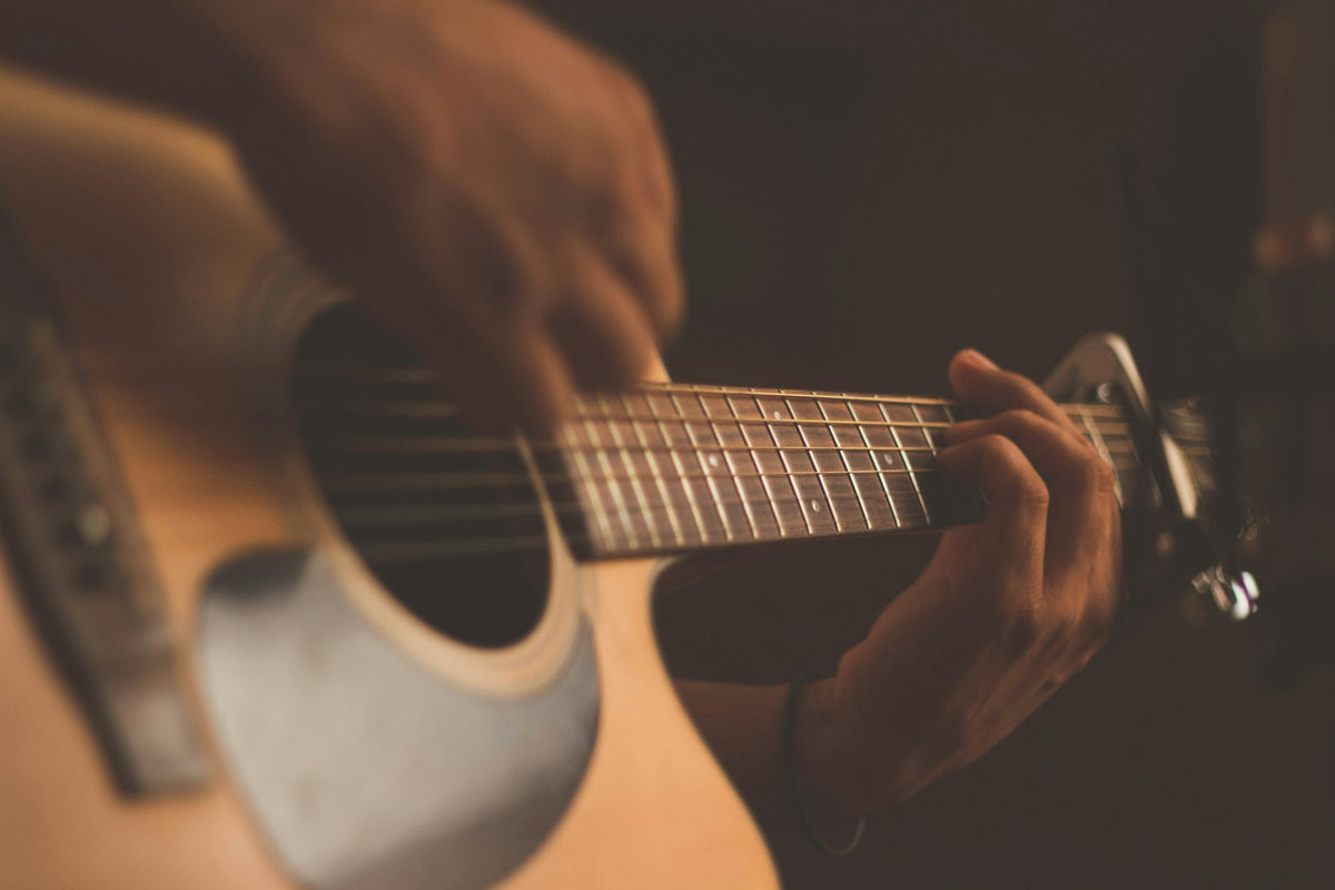 Hands playing an acoustic guitar