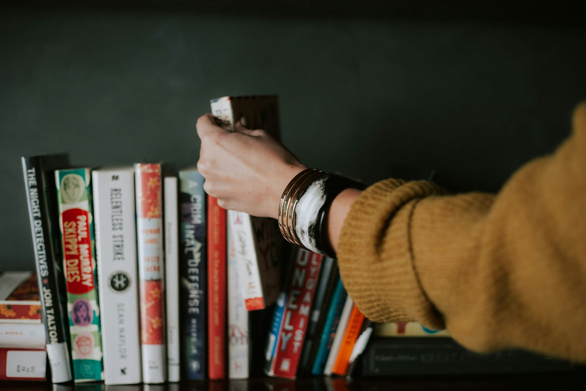 Hand reaching for a book on a shelf