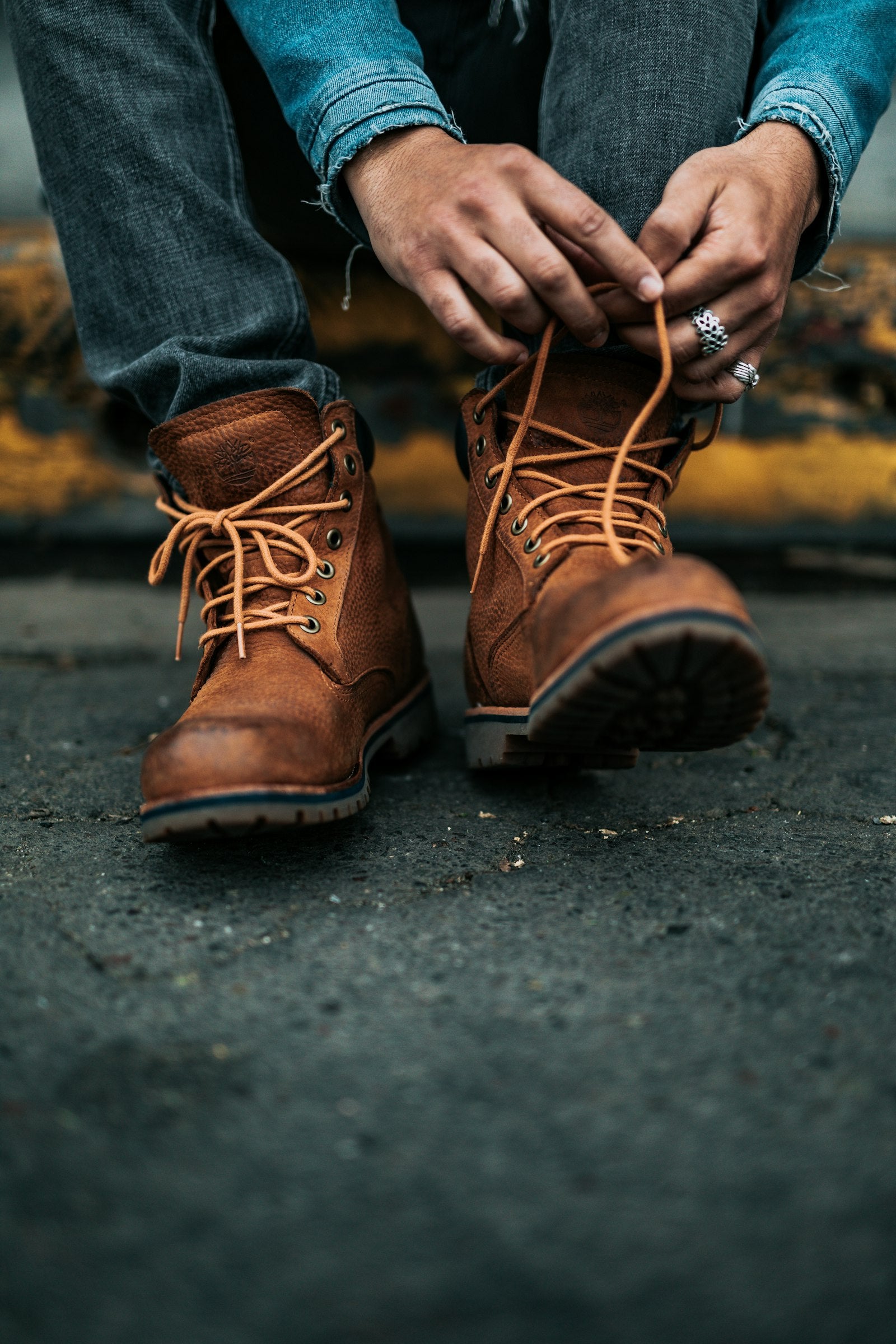 Tan leather lace-up boots being laced on a kerb