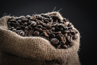 Roasted coffee beans spilling from a burlap sack