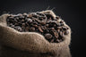 Roasted coffee beans spilling from a burlap sack