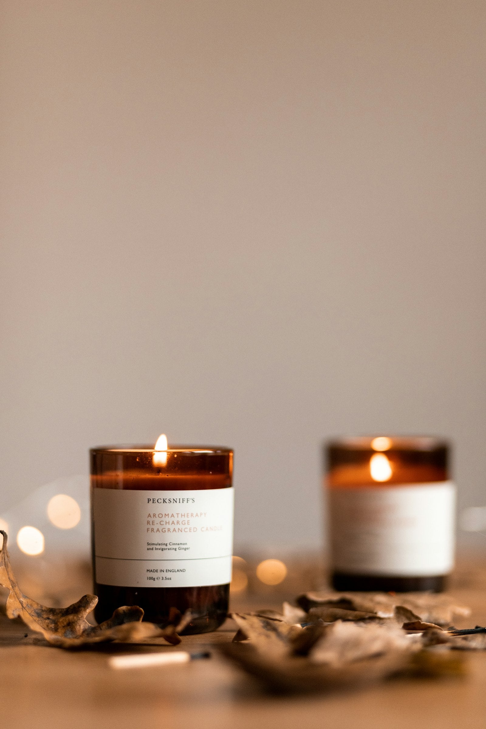 Two amber glass candle jars lit on a pale surface