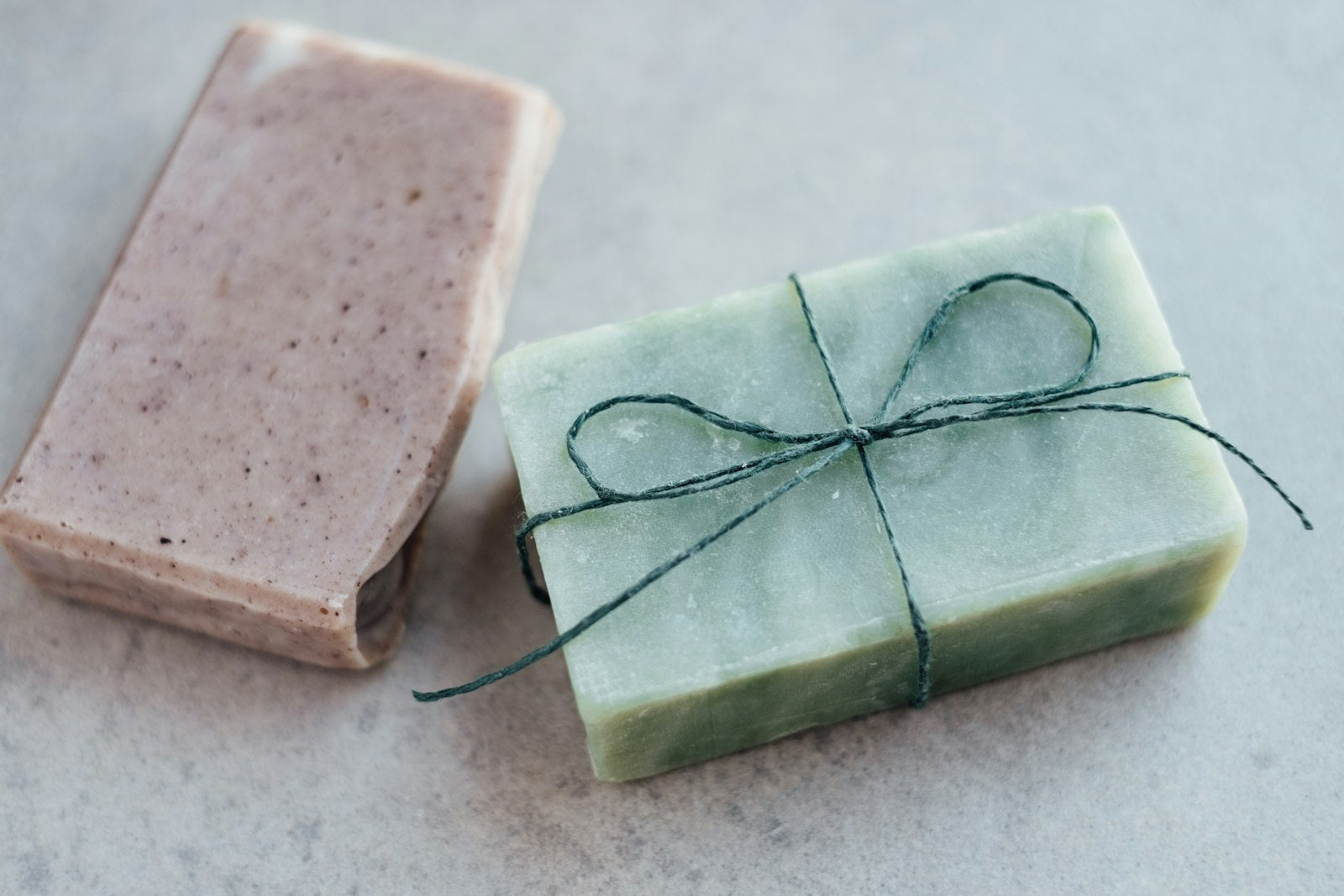 A pink clay soap bar and a green sage bar tied with twine