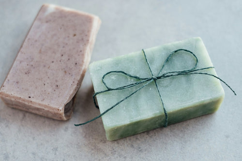 A pink clay soap bar and a green sage bar tied with twine