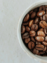 Light-roasted coffee beans in a white ceramic bowl