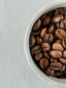 Light-roasted coffee beans in a white ceramic bowl