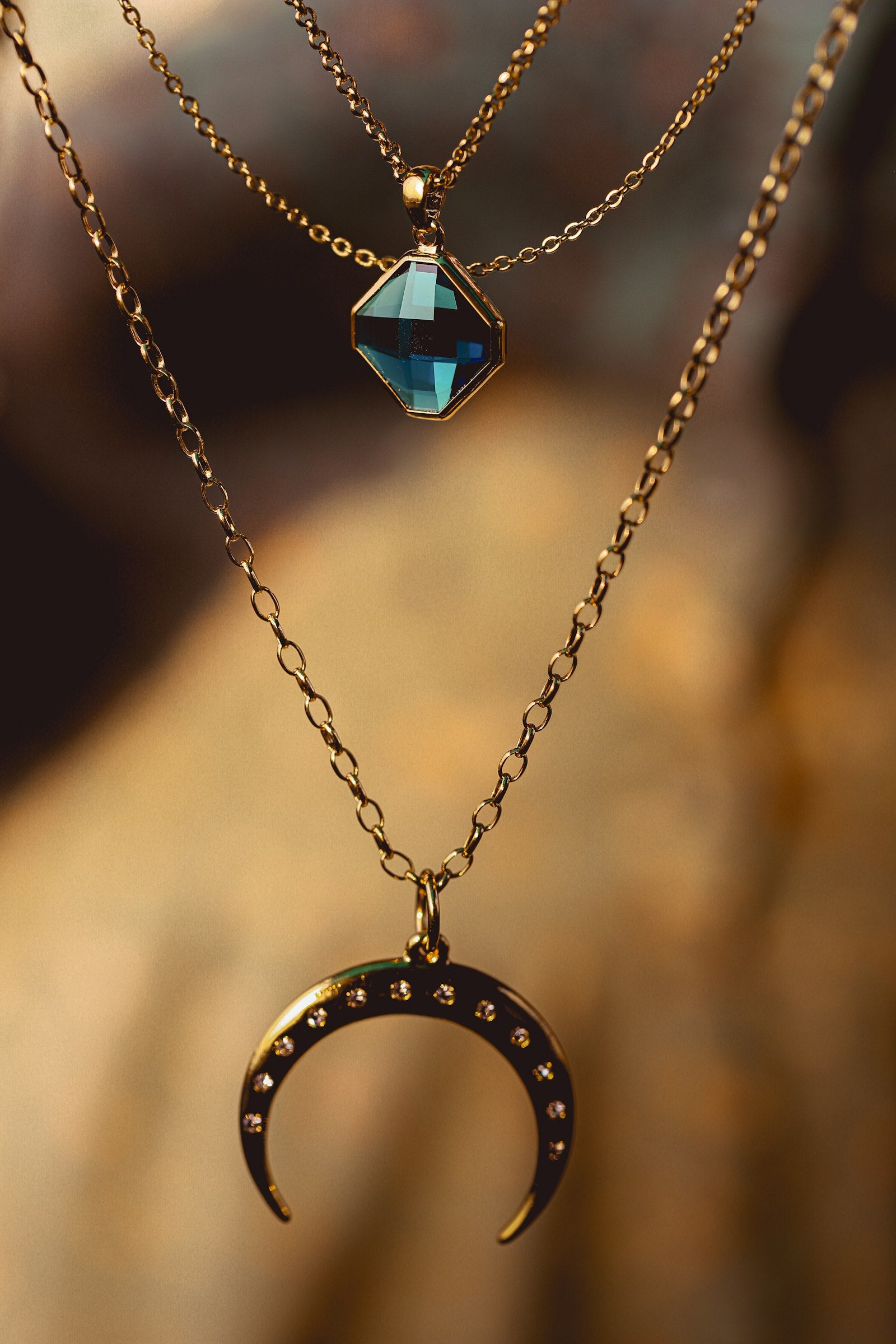 A gold crescent pendant layered with a gemstone necklace