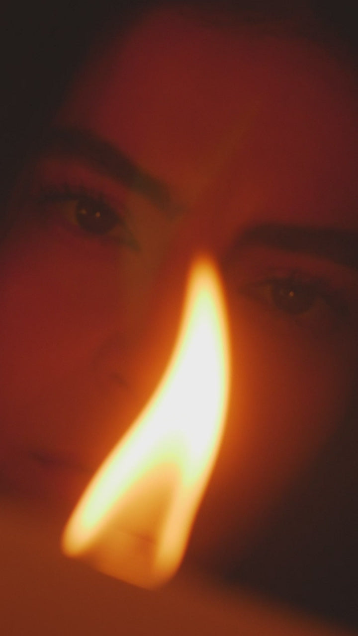 A tall candle flame lit in front of a face