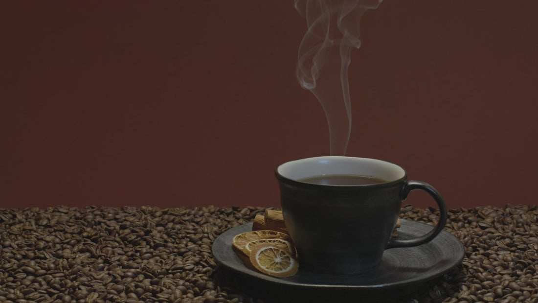 A black cup steaming on a bed of roasted beans