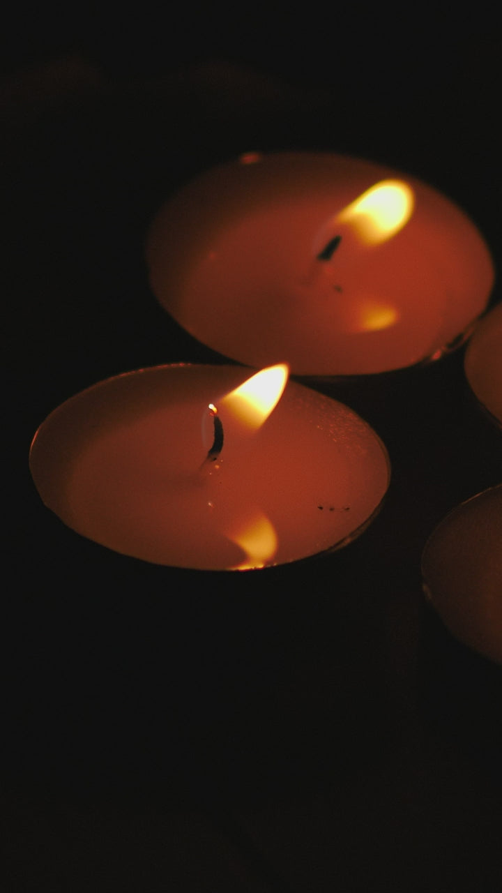 A cluster of tealights burning in the dark