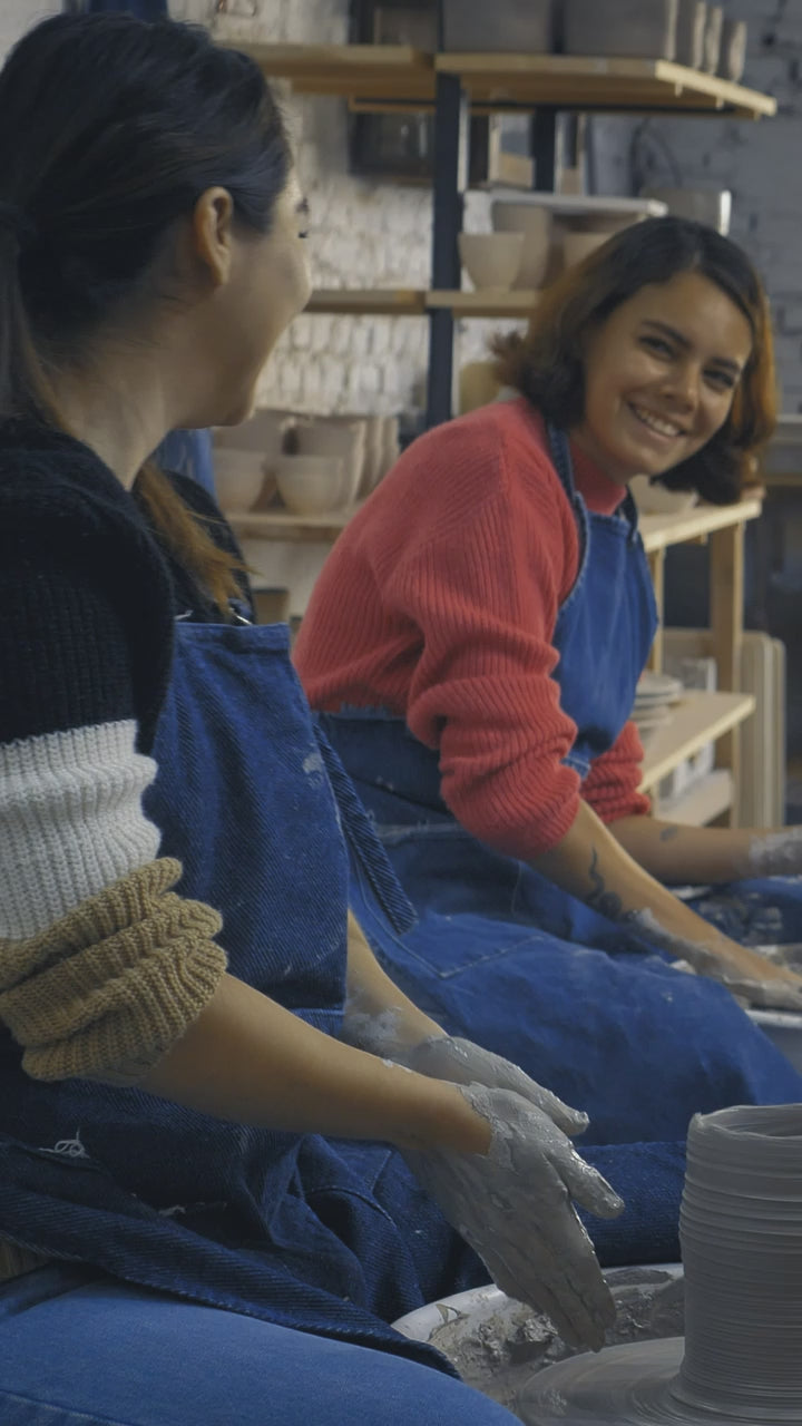 A potter throwing a ribbed vessel at a studio bench