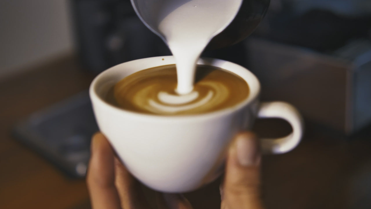 A finished latte art rosetta held in two hands