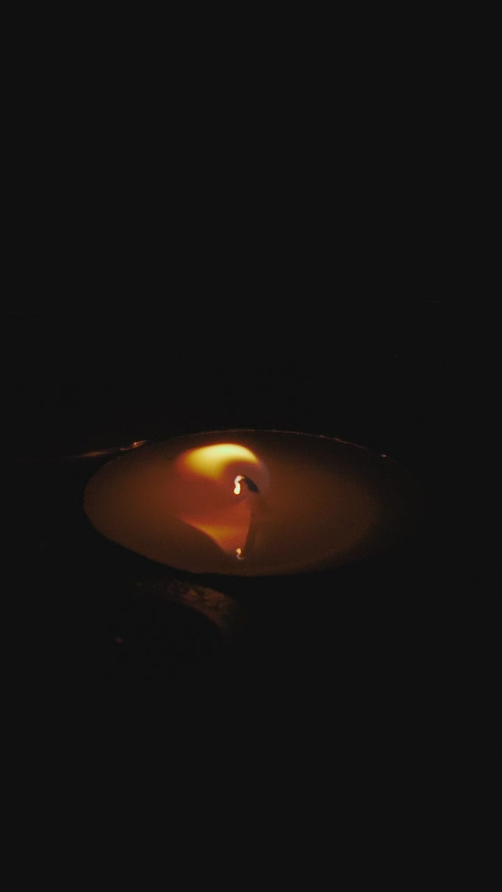 A single tealight flame against black