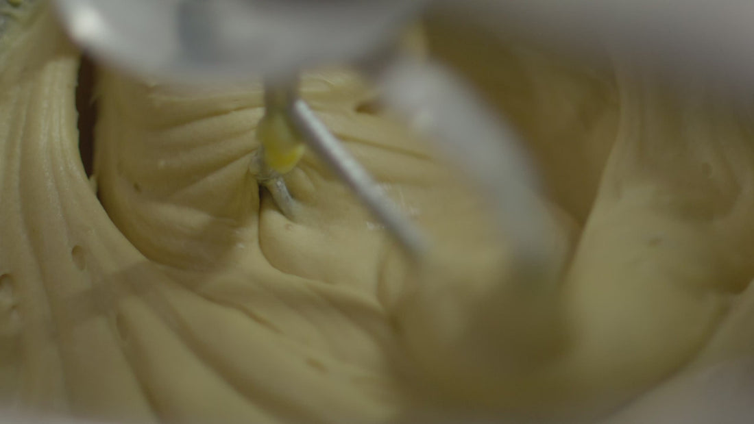 A beater folding through pale cake batter