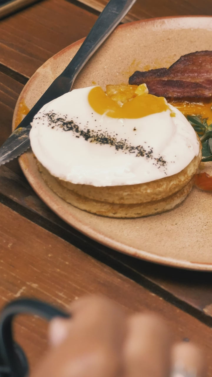 A cast-iron teapot beside a slice of cake on a wooden table