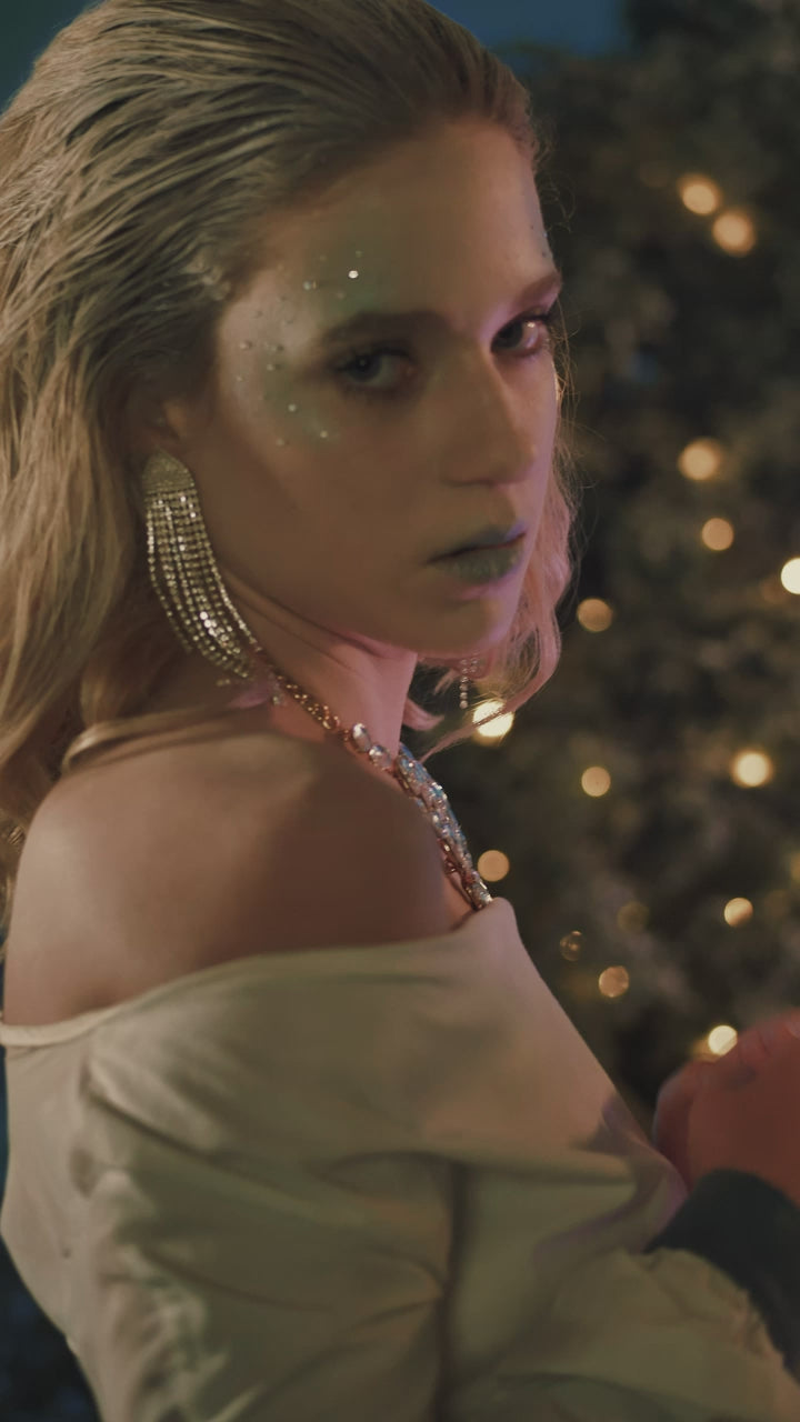 A statement necklace and drop earrings under warm light