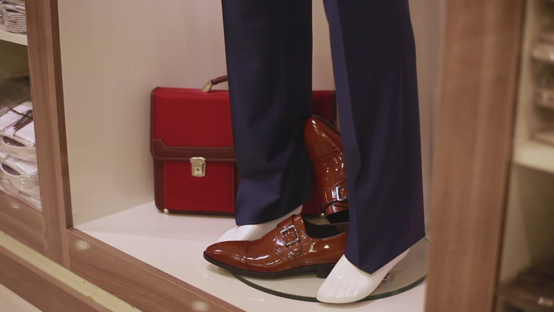 A customer trying on a polished leather loafer in a shop
