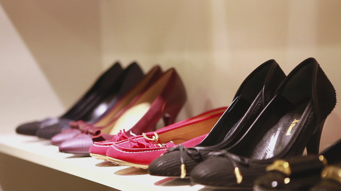 A hand lifting a shoe from a display of leather footwear