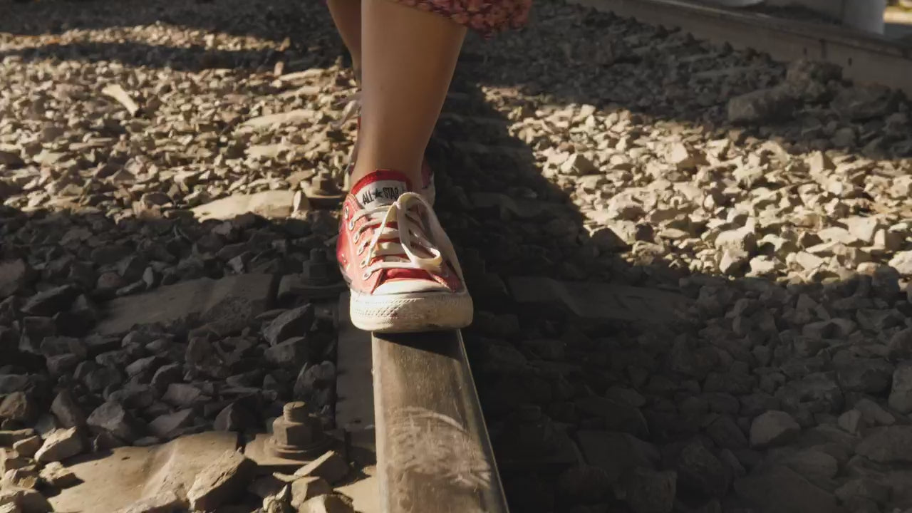 Sneakers walking along a sunlit rail