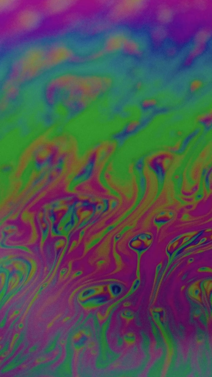 Iridescent soap film swirling in green and violet