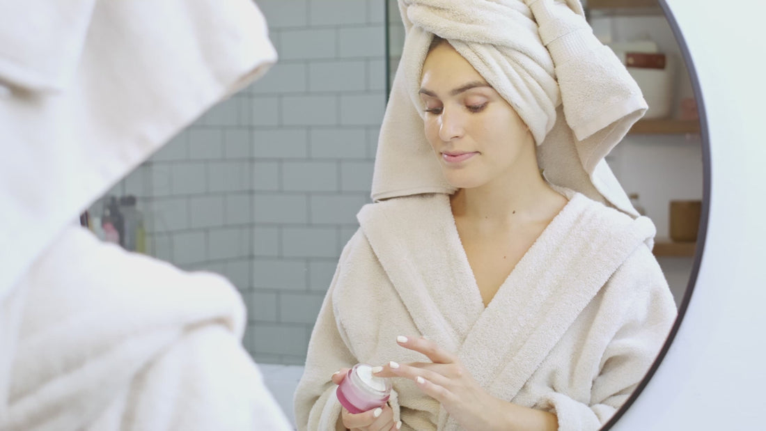 Two people in robes doing a skincare routine at a mirror