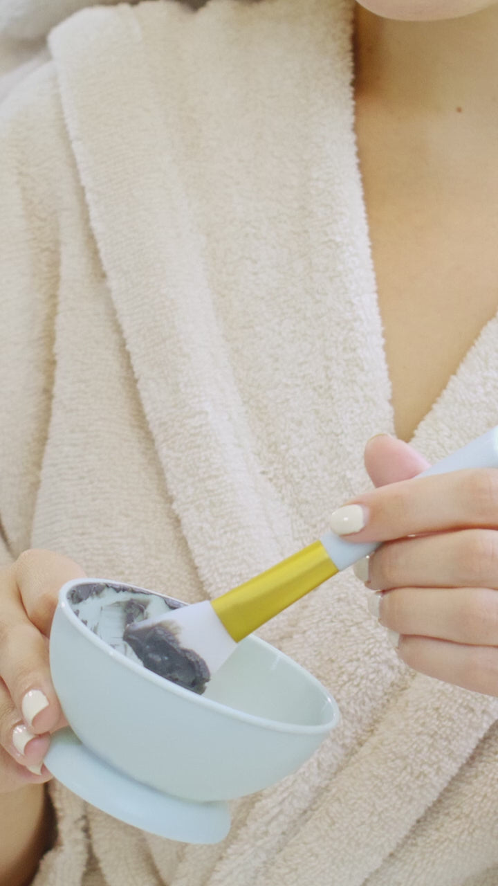 Brushing a clay mask onto the cheekbone